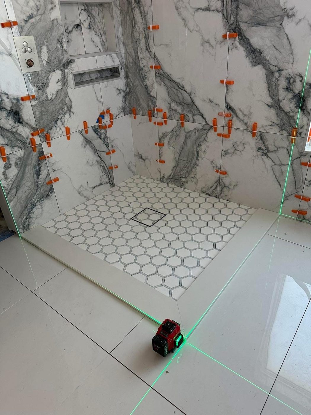Douche aux murs en grands carreaux et au sol en mosaïque hexagonale
